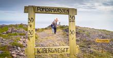Ungdom tar bilder på toppen av Domen-fjellet. Vi ser dem gjennom en treramme som er laget for at folk skal ta bilder. 